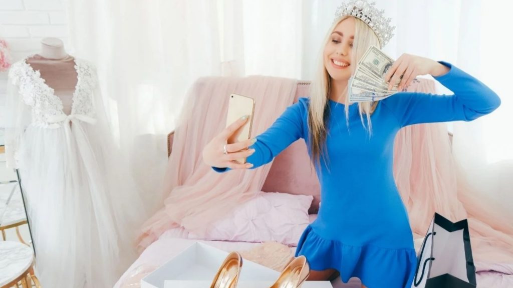 Young woman taking a selfie with money