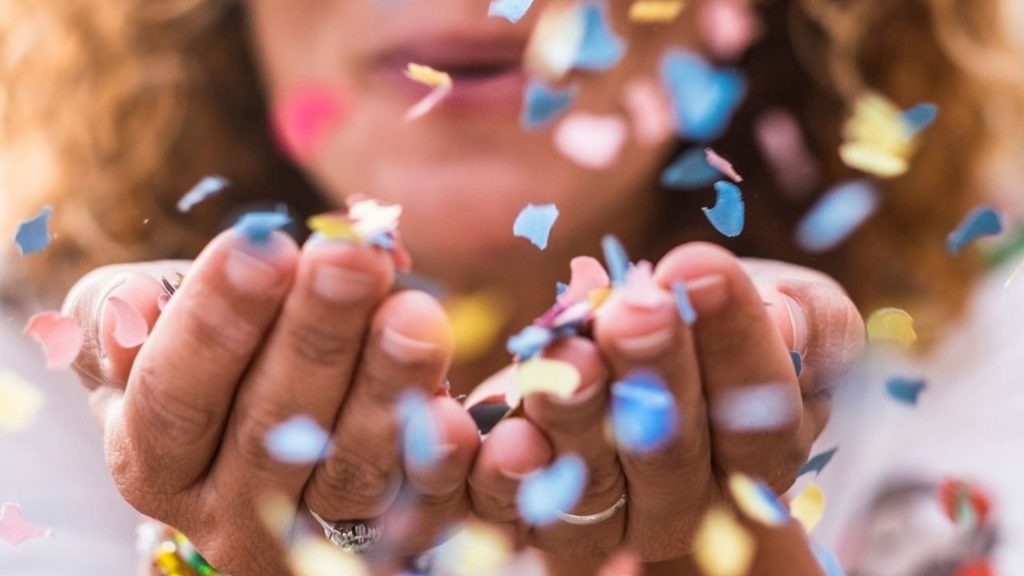Woman blowing confetti from her hands